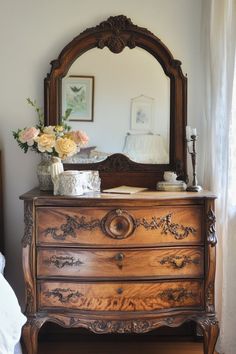 an antique dresser with flowers and a mirror