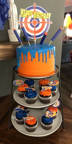 a birthday cake with cupcakes in front of it and an arrow on top