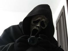 a person with a camera in their hand wearing a skeleton mask and holding a camera