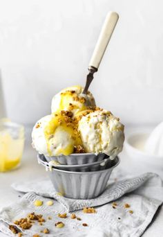 two scoops of ice cream sitting in a metal cup on top of a table