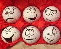 six golf balls with faces drawn on them in a red box, all lined up