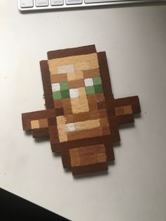 a wooden cut out of an old video game character on a computer desk next to a keyboard