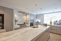 a large kitchen with marble counter tops and stainless steel appliances, along with an island