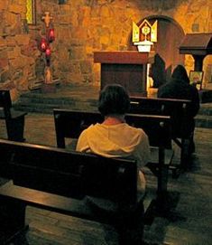 people are sitting in pews at the alter of a church with stone walls and stained glass windows