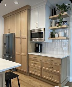 a kitchen with white counter tops and wooden cabinets, along with a stainless steel refrigerator