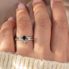 a woman's hand with a black diamond ring on top of her left hand