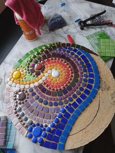 a table topped with lots of different colored tiles and crafting supplies on top of it