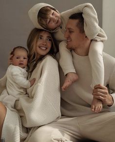 a man, woman and child are sitting on a bed together in matching sweaters