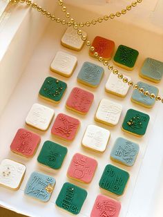 a box filled with lots of different colored cookies on top of a table next to a gold chain