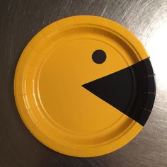 a yellow and black paper plate sitting on top of a metal surface with an upside down design