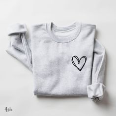 "Heart sweatshirt, Pocket Heart Hoodie, Heart Sweatshirt, Heart Outline Hoodie, Cute Hoodie, Cute Sweatshirt, gifts for her, sweatshirt gift How to Order 1* View all color and size charts before you place your order. 2* Select your shirt \"SIZE\" and \"COLOR\". 3* Click add to cart.  If you are ordering more than 1 item, you need to repeat this process for each item you wish to order. Product Information Gildan Hoodie- Sweatshirt 8 oz.(US) 13.3 oz.(CA), 50/50 preshrunk cotton/polyester Heather S Crop Crewneck, Club Sweatshirts, Heart Sweatshirt, Moms Club, Mama Sweatshirt, Emergency Room, Sweater Gift, Knit Sweatshirt, Casual Sweatshirt