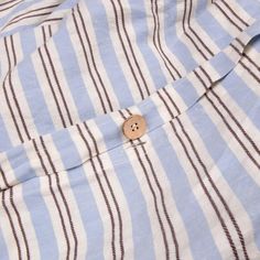 a button on a blue and white striped shirt with brown pins in the chest pocket