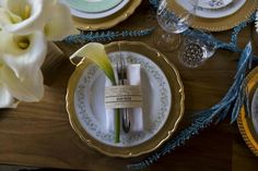 the table is set with dishes, silverware and flowers