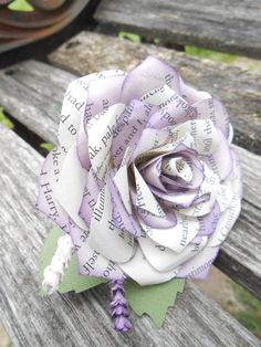 a purple and white rose sitting on top of a wooden bench next to an old book page