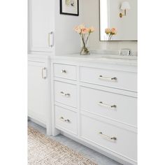 a bathroom with white cabinets and flowers on the counter