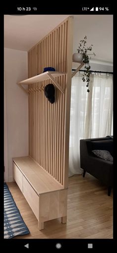 a wooden shelf with a hat on it in front of a black chair and window