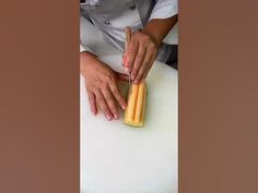 a person cutting up food on top of a white counter