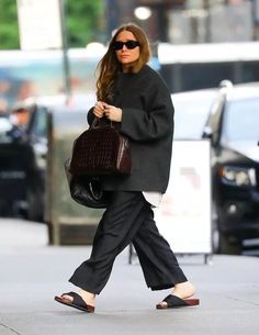 a woman walking down the street carrying a purse