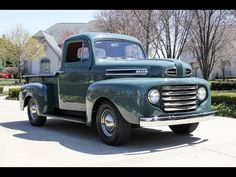 an old green truck parked in front of a house