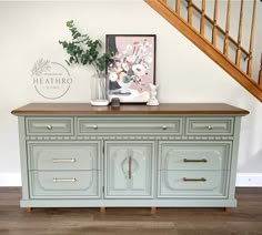 an old dresser is painted blue with gold handles and brass pulls on the drawers, along with a plant in a vase