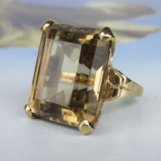 This classic Mid-Century cocktail ring circa 1960 holds a large approximately 25ct smoky color step cut citrine in a 14k yellow gold setting. This ring is lively and glamorous, with great, subtle color-- it is golden all over! Currently size 6.25 and can be resized as needed. One resizing provided, please allow one week. Natural Citrine measures 20 x 16 x 11.7mm and weighs approximately 25.00ct. Citrine is in good condition with minor instances of wear but no serious chips. Citrine secure in set Edwardian Ring, Ring Emerald Cut, Sparkly Wedding, Vintage Cocktail Ring, Ring Emerald, Victorian Rings, Step Cut, Antique Engagement, Yellow Gold Setting