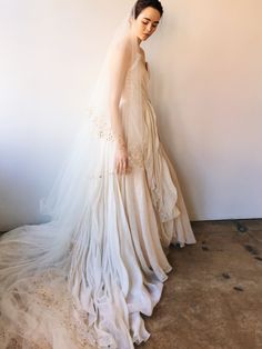 a woman in a wedding dress standing next to a wall