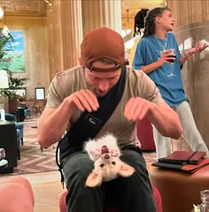 a man sitting on top of a chair holding a small white kitten in his lap