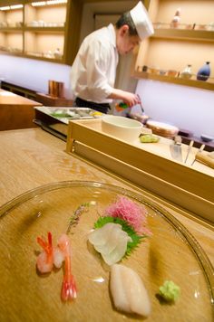 a chef preparing food in a kitchen with chopsticks on the counter and plates