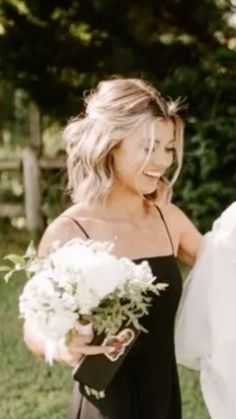 a woman in a black dress holding a white bouquet