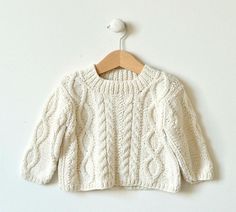 a white sweater hanging on a wooden hanger