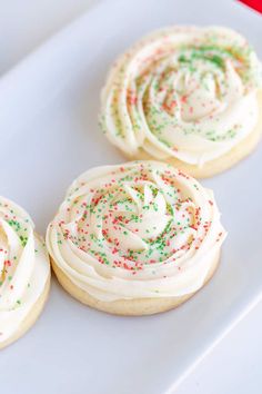 four decorated cookies on a plate with sprinkles and white frosted icing