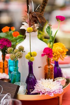 colorful vases and flowers are on a table with other items in the foreground