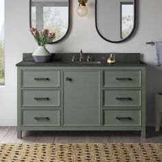 a bathroom vanity with two mirrors above it and a rug on the floor next to it