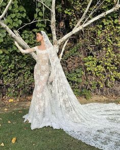 a woman in a wedding dress standing next to a tree