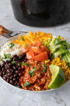 a white bowl filled with mexican food on top of a marble counter next to a fork