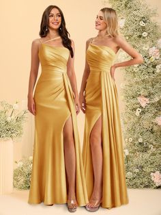 two women in gold dresses standing next to each other with their legs slited up