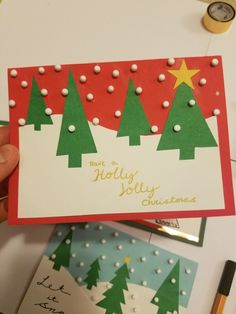 someone holding up a christmas card with trees on it