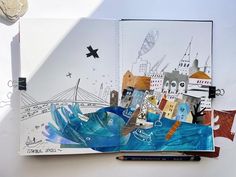 an open book with drawings on it and a pen in front of the pages that have been altered to look like cityscapes