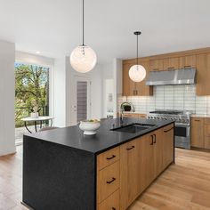 a large kitchen with wooden cabinets and black counter tops, along with an island in the middle