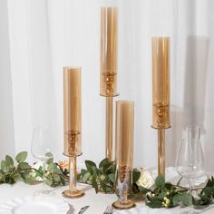 the table is set with gold candlesticks and greenery