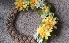 a wreath made out of rope and flowers on the floor, with yarn around it