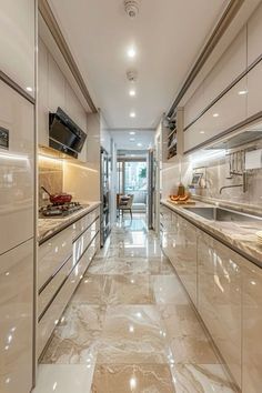 a long narrow kitchen with marble counter tops and stainless steel appliances on either side of the cabinets