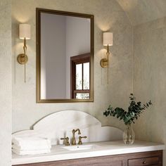 a bathroom with a sink, mirror and vase on the counter top in front of it