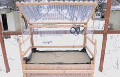 a wooden structure with plastic coverings on top in the middle of snow covered ground