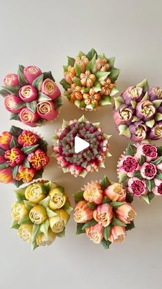 a bunch of fake flowers sitting on top of a white table next to each other