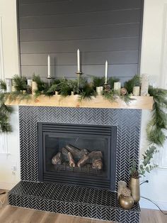 a decorated fireplace with candles and greenery