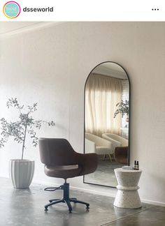 a chair and mirror in a room with white walls, flooring and concrete floors