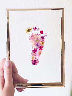 a person holding up a painting with flowers on it