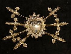 an ornate gold brooch with heart surrounded by crosses