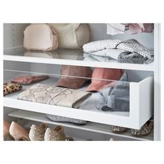 several pairs of shoes and purses are on display in a white shelf with glass shelves